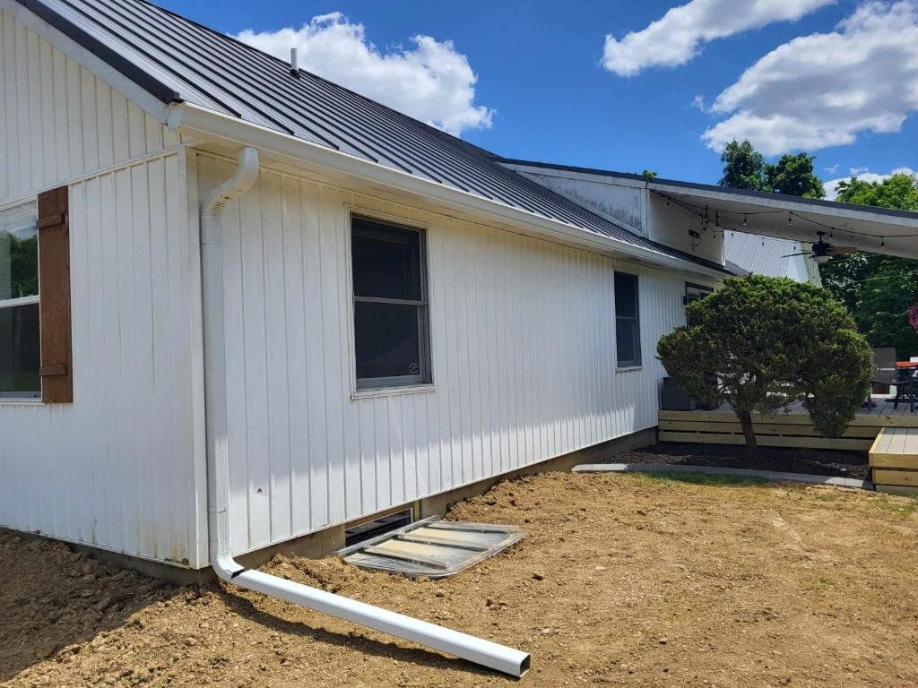 Newly installed white seamless gutter and downspout on a Cincinnati home, blue sky