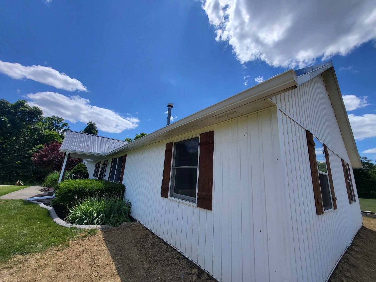 Clean new gutter line on a white-sided Cincinnati home against blue sky